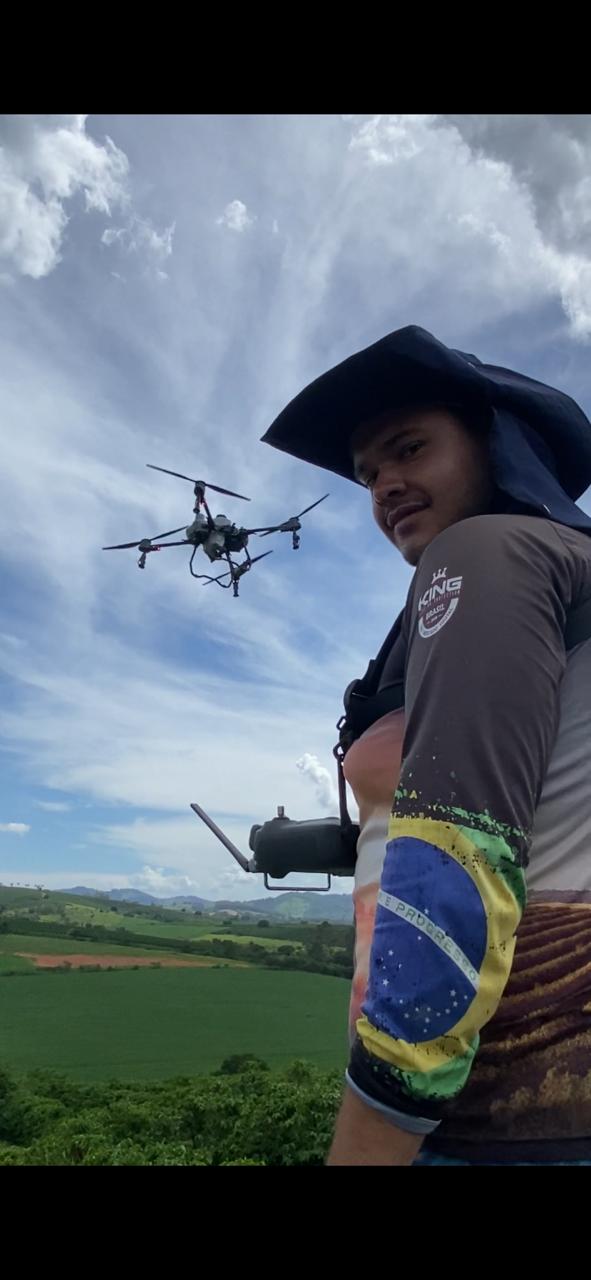 Piloto da PH Drones acompanhando o drone sobre a lavoura